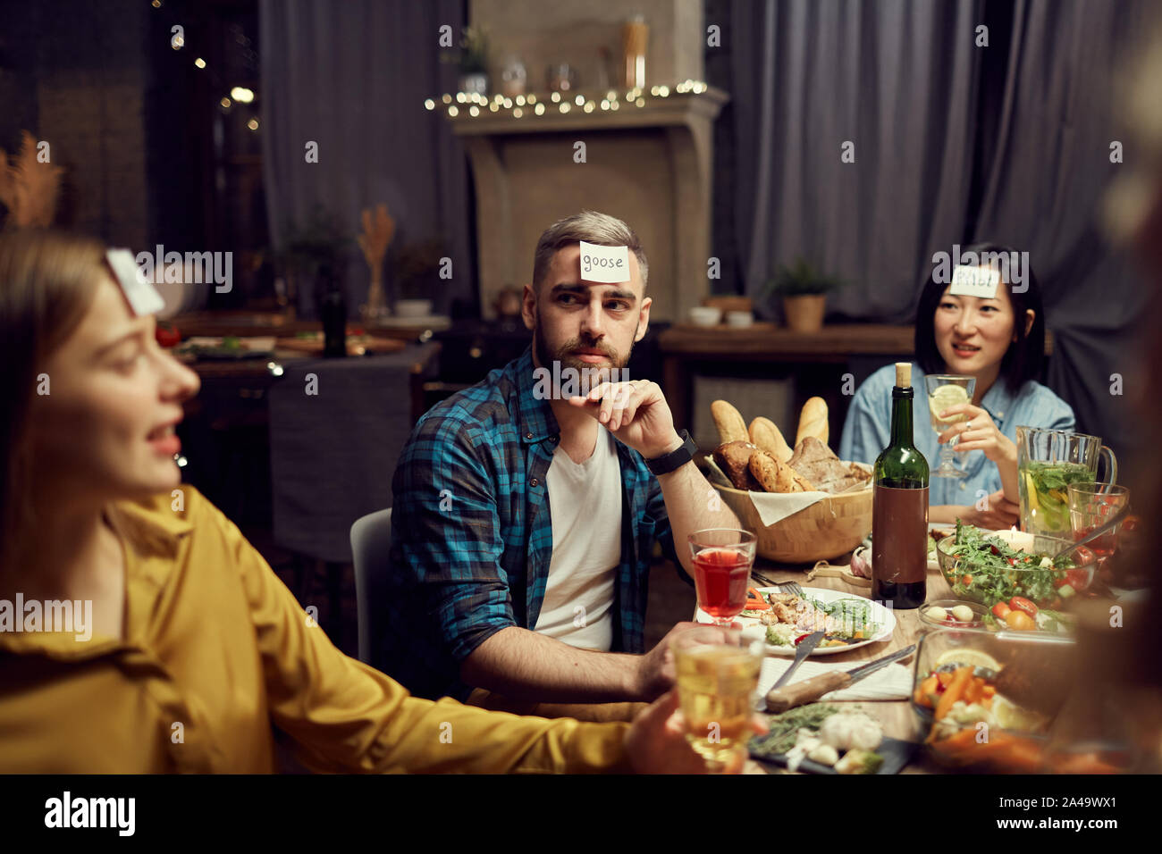 Gruppo di persone che giocano a indovinare mentre è seduto al tavolo di gustare la cena party in camera oscura, spazio di copia Foto Stock