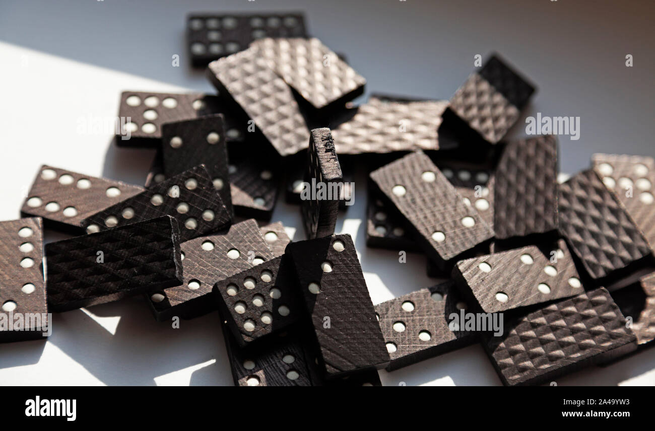 Un sacco di domino giacente nel caos sul tavolo soleggiato Foto Stock