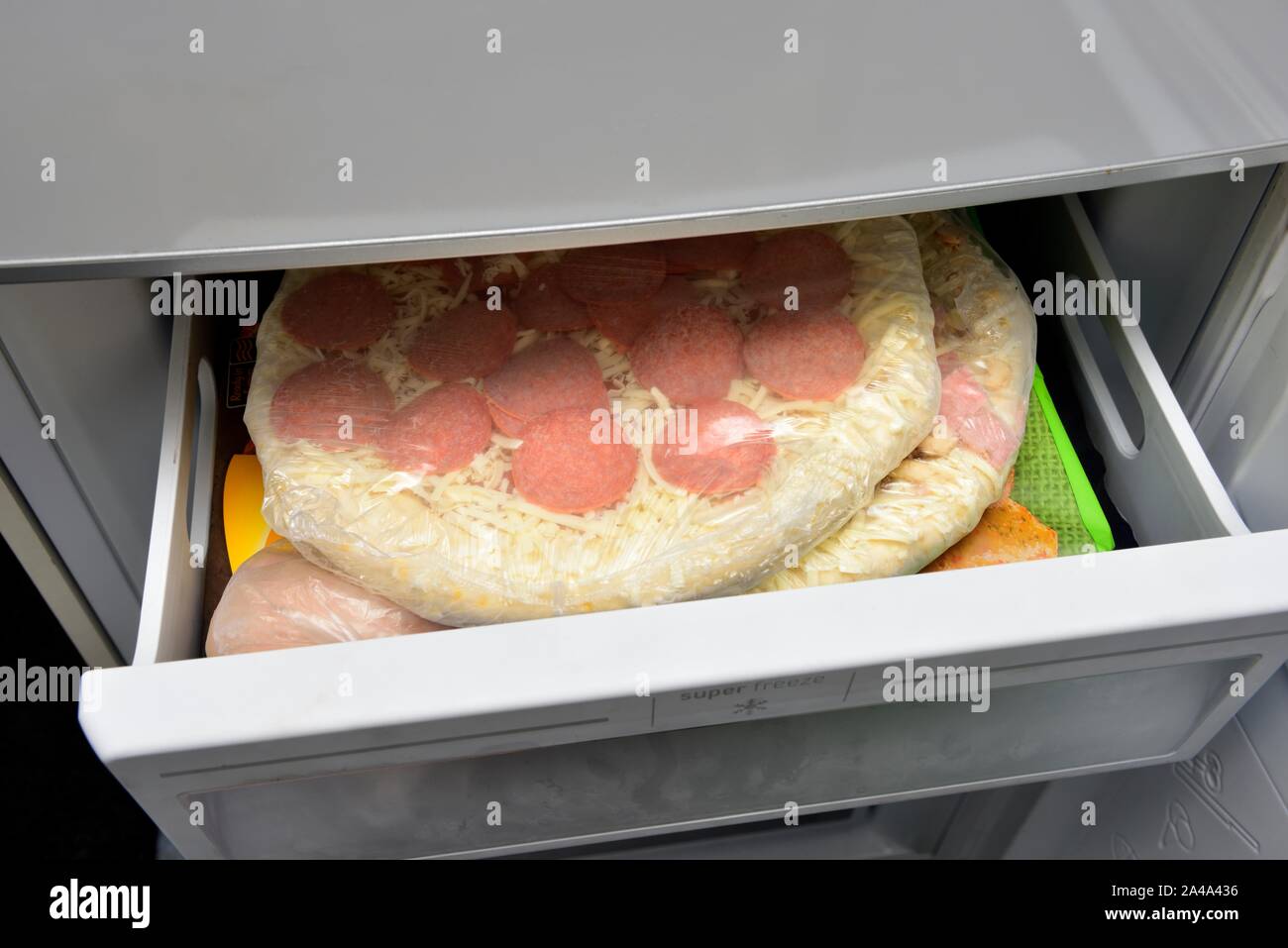 Salsiccia per pizza pizza congelata in un congelatore aperta disegnare Foto Stock