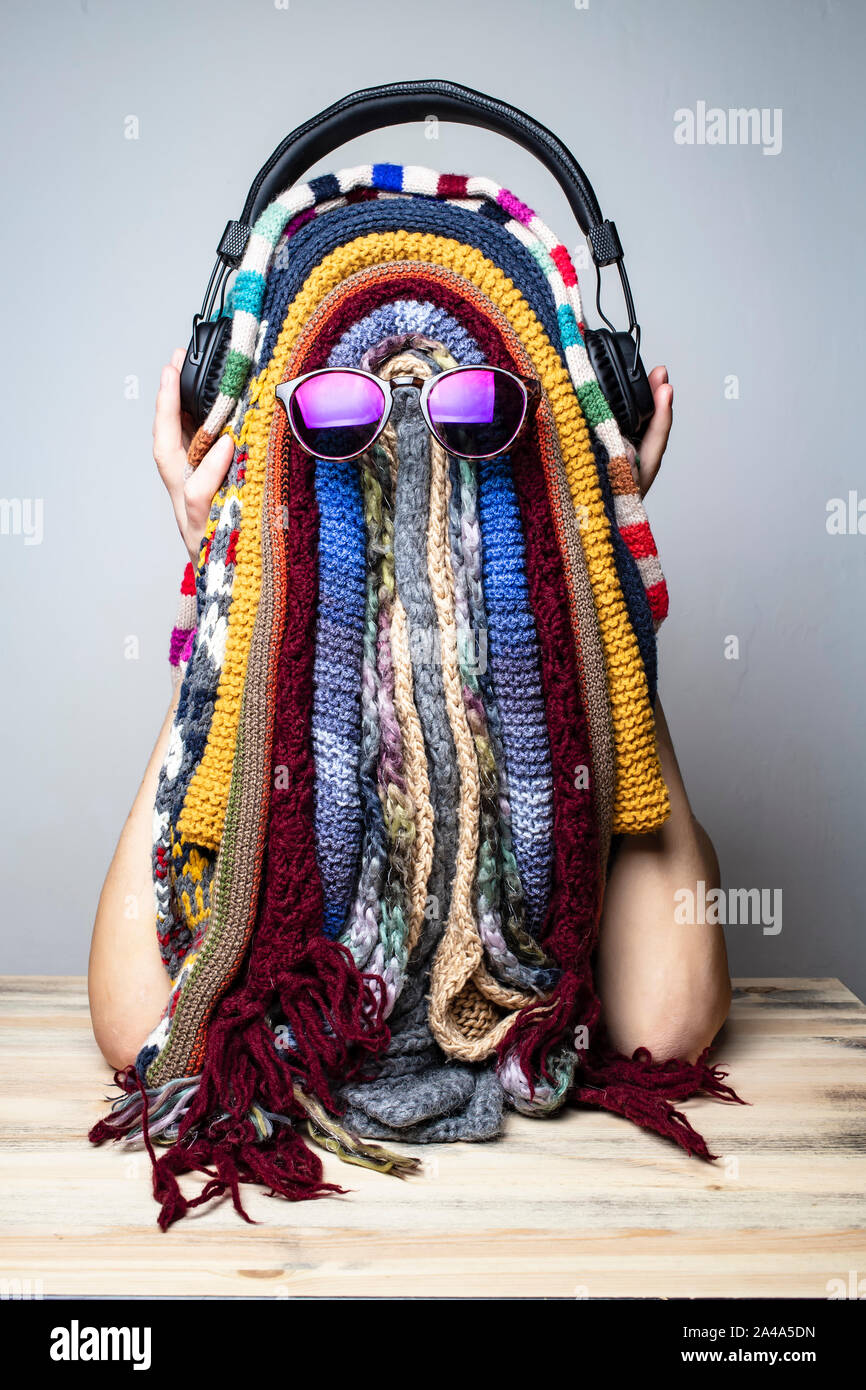 Ragazza è ingannare circa in inverno durante l'attesa per l'estate e scherzosamente fatto una divertente maschera di sciarpe multicolore a forma di rastaman faccia Foto Stock