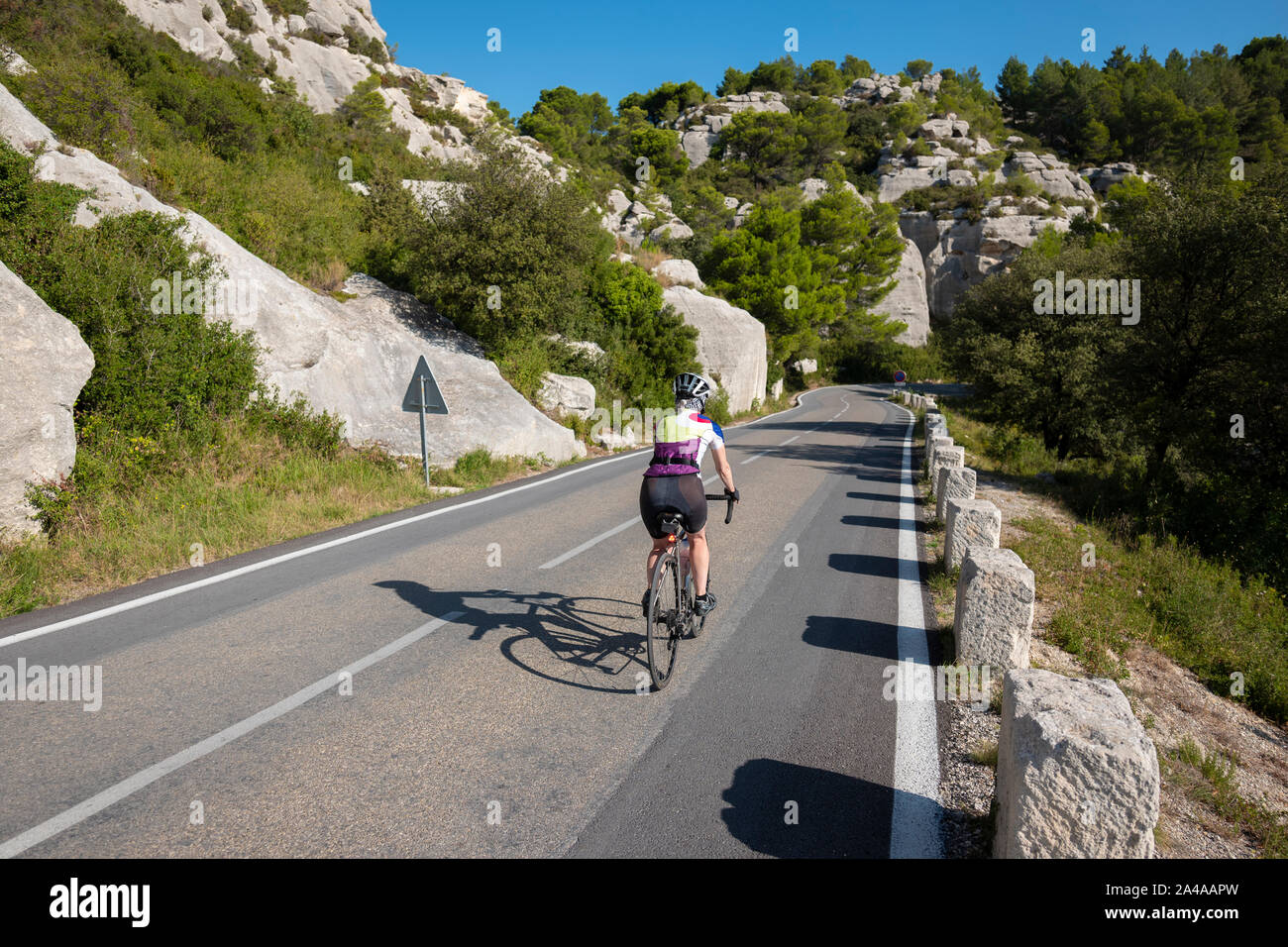 Ciclista femmina in bicicletta attraverso le Alpilles, vicino a San Remo, Francia. Foto Stock