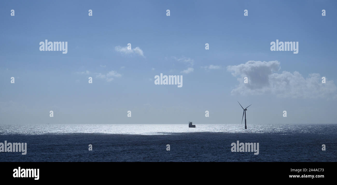 Seascape dopo l'alba, cielo blu con nuvole e turbine eoliche sul mare Foto Stock