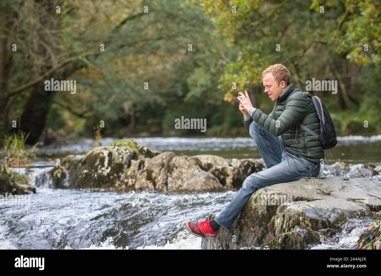 L'uomo sulle sponde rocciose del Pont-y-coppia cade sul Afon Llugwy, Betws-y-Coed, Wales, Regno Unito Foto Stock