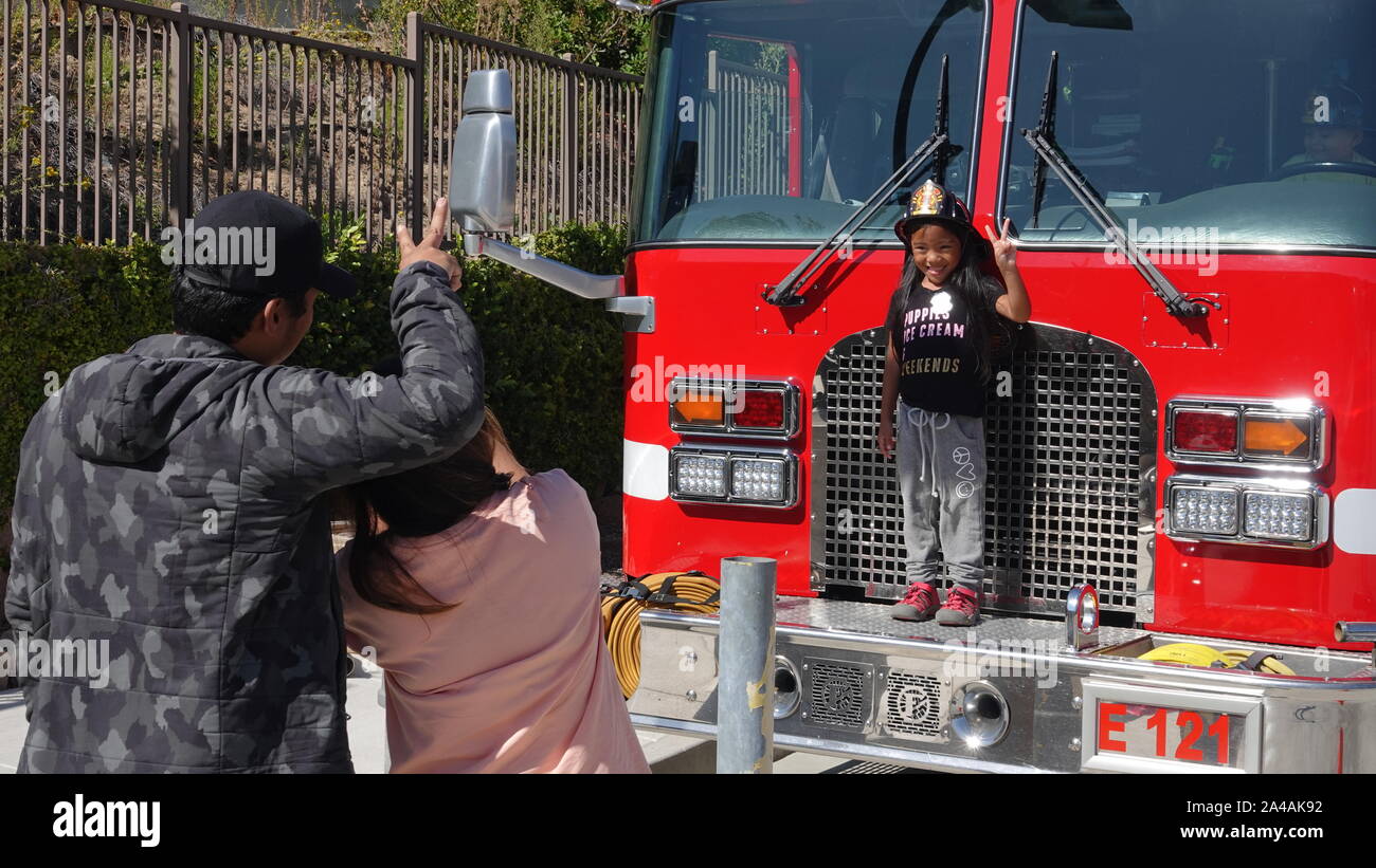 I genitori prendere le foto dei loro bambini come arrivare a esplorare il camion dei pompieri presso la stazione dei vigili del fuoco open house Foto Stock