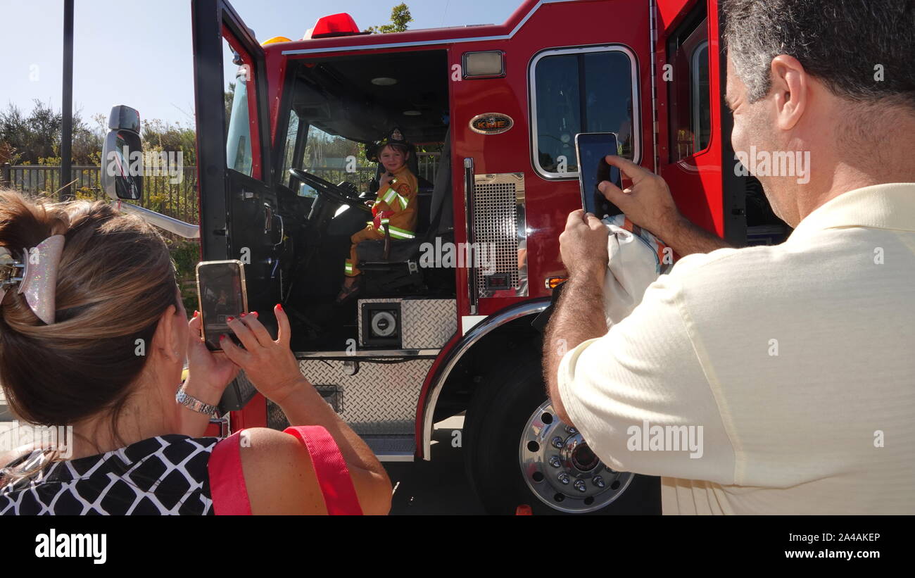 I genitori prendere le foto dei loro bambini come arrivare a esplorare il camion dei pompieri presso la stazione dei vigili del fuoco open house Foto Stock