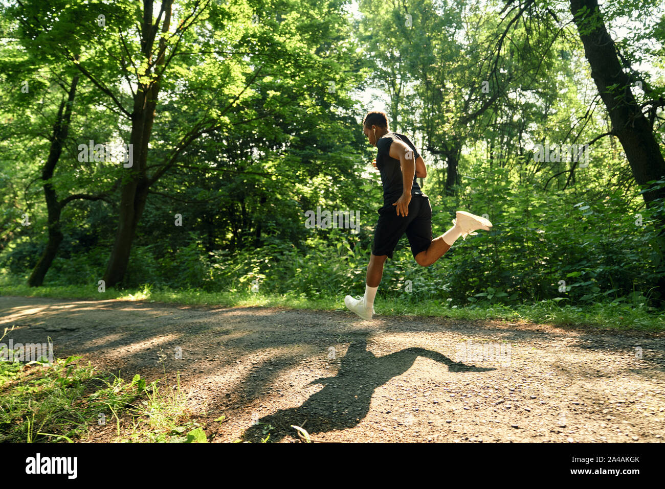 Sportivo africani in esecuzione sulla passerella del parco nella mattina di sole. Muscolare, Hardy atleta in calze bianche e bianco sneakers. Concetto di salute, di motivazione e di sport. Foto Stock