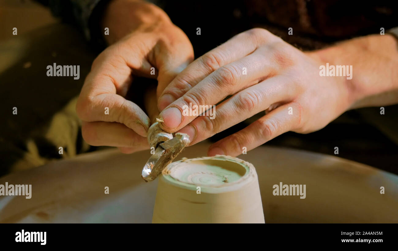 Professional potter carving mug con l'attrezzo speciale nel laboratorio di ceramica Foto Stock