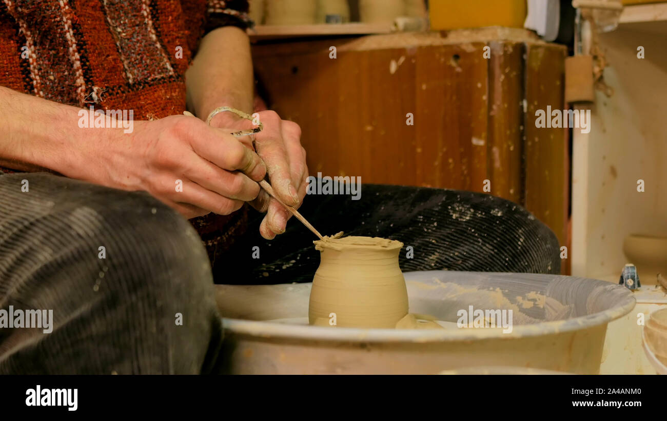 Professional potter carving mug con l'attrezzo speciale nel laboratorio di ceramica Foto Stock