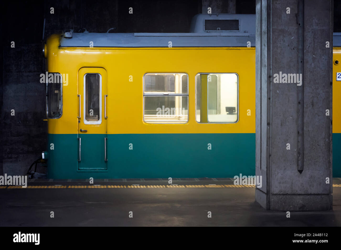 È arrivato il treno per la stazione ferroviaria. Giallo - Verde Blu allenatore della testa del treno, Windows e una porta e la piattaforma. Foto Stock