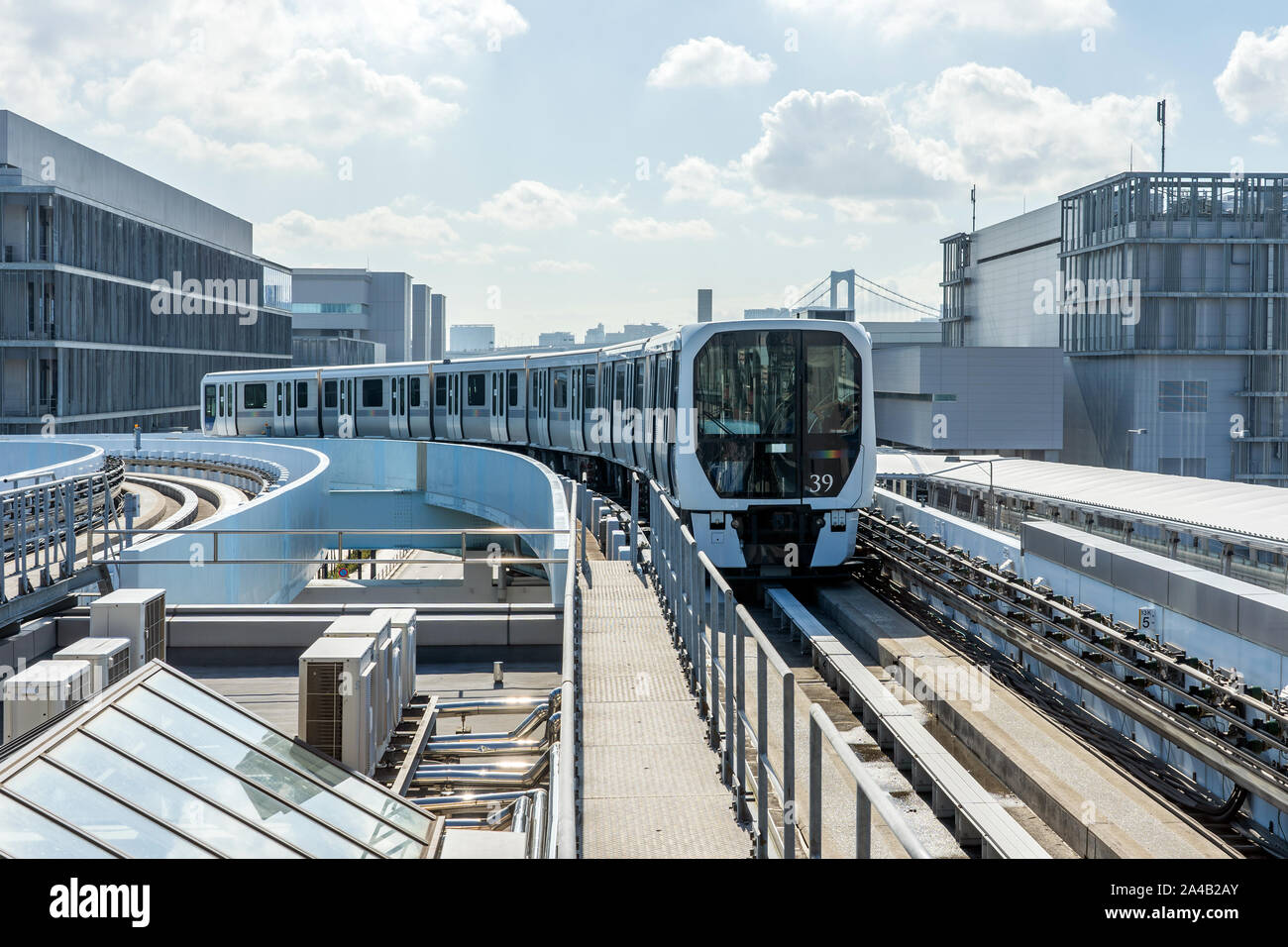 Il treno monorotaia si sta avvicinando alla stazione su una giornata di sole. Il bianco Metro treno arriva alla piattaforma in aria aperta la via a Tokyo in Giappone. Foto Stock
