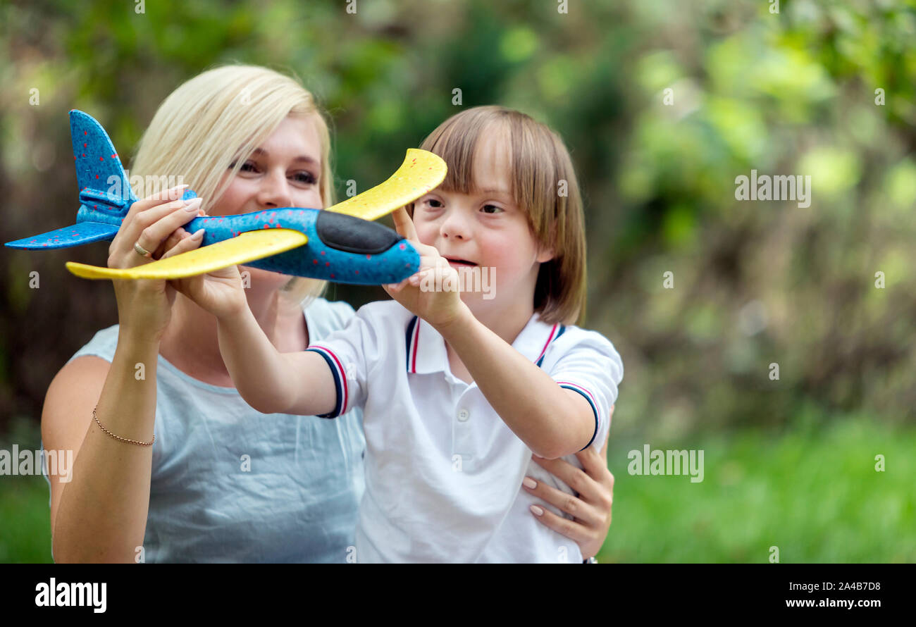 Madre premurosa e il suo sunny kid giocando con un aeroplano giocattolo sul park Foto Stock