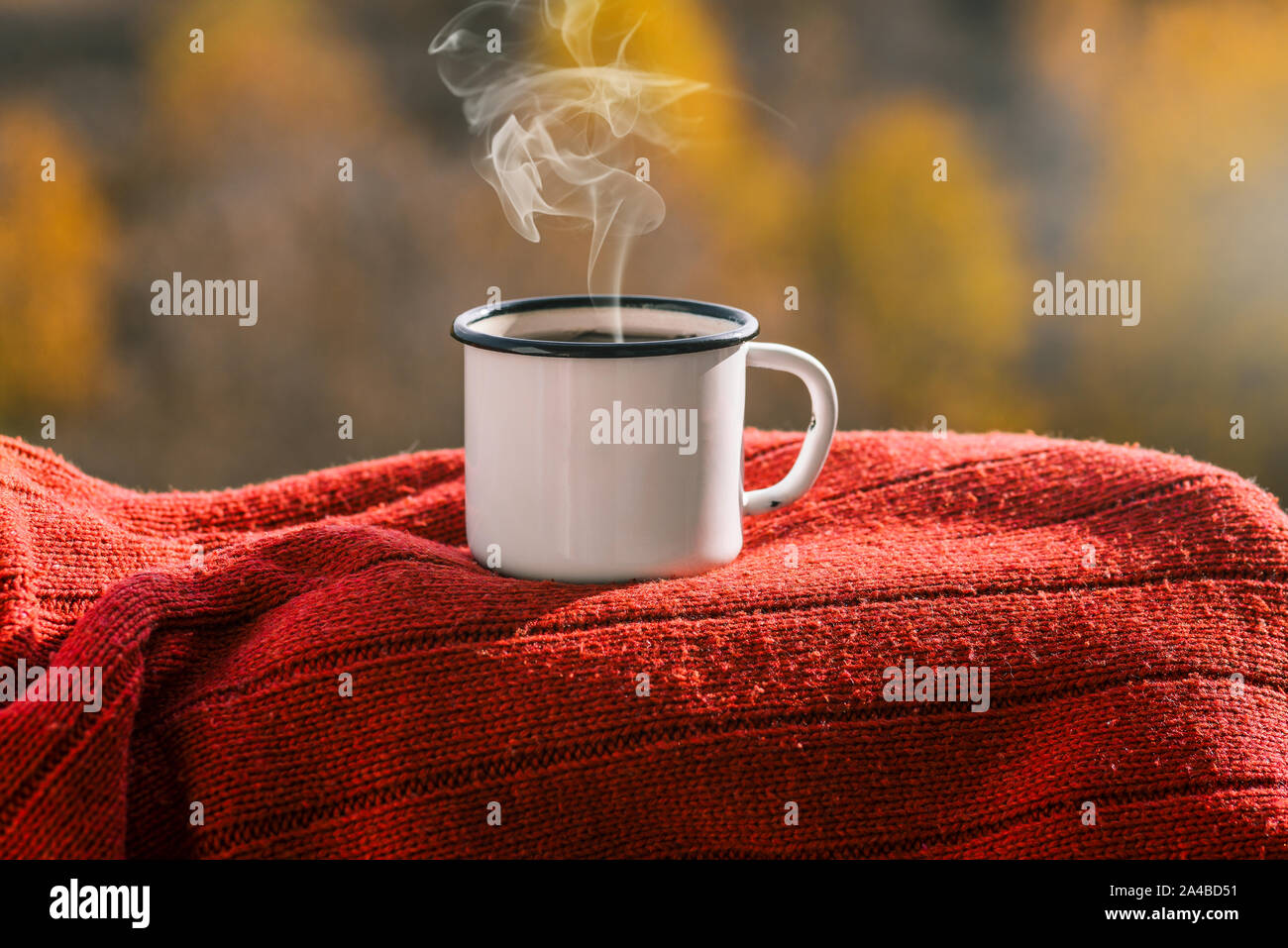 Boccale di ferro con tè su un autunno sfondo. La tazza su un maglione rosso. Tazza fumante. Concetto di autunno e inverno si avvicina. Vestiti caldi. Foto Stock
