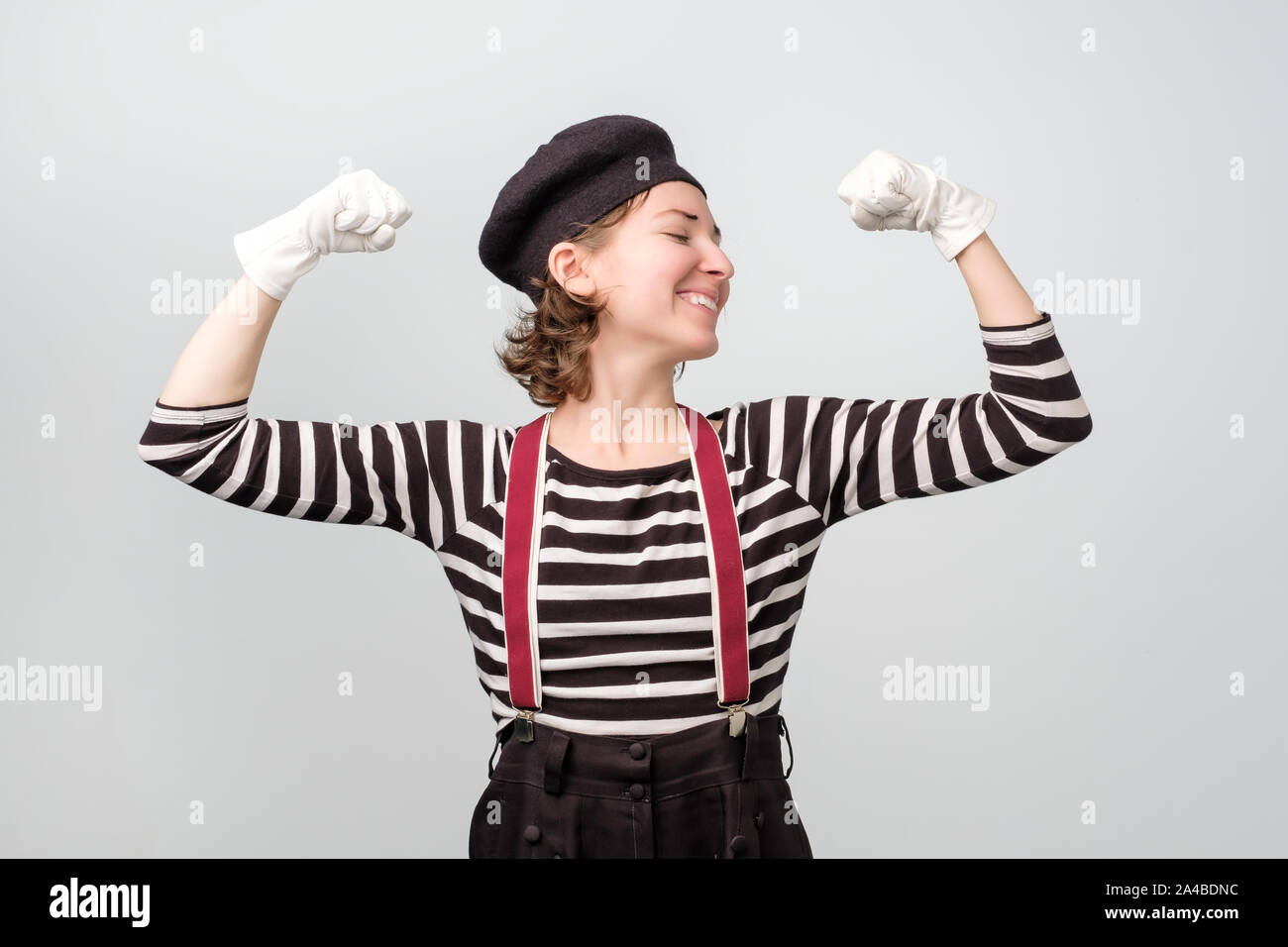 Donna forte mostrando il suo muscularity. Funny mime che mostra la sua potenza Foto Stock