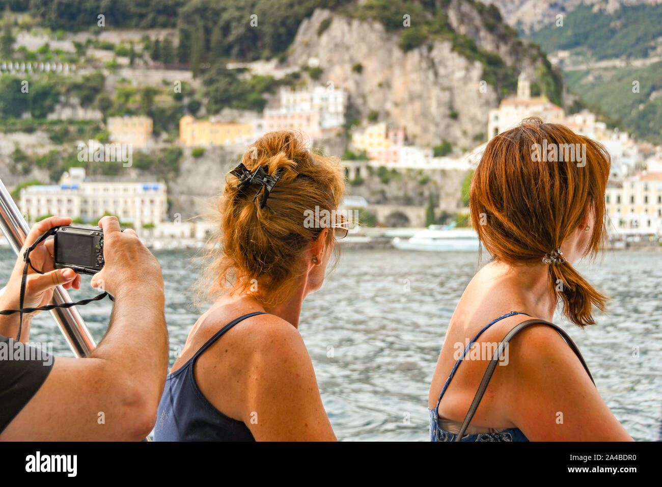 Costiera Amalfitana - Agosto 2019: persone su una barca a guardare la costiera amalfitana. Un'altra persona è scattare una foto su una piccola telecamera. Foto Stock