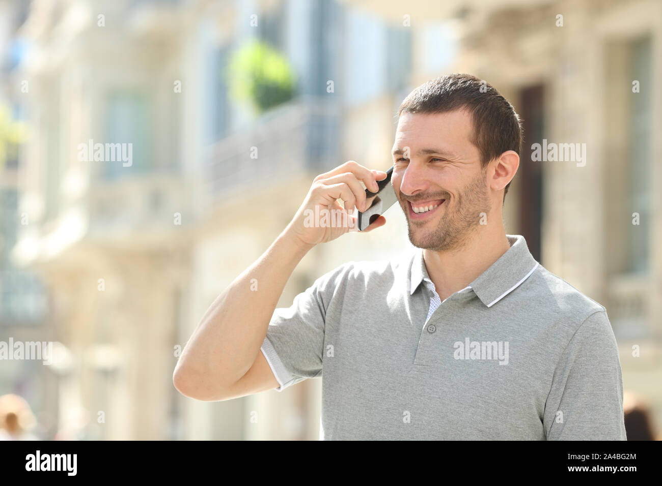 Felice l'uomo adulto parlando al telefono mobile a piedi in strada Foto Stock