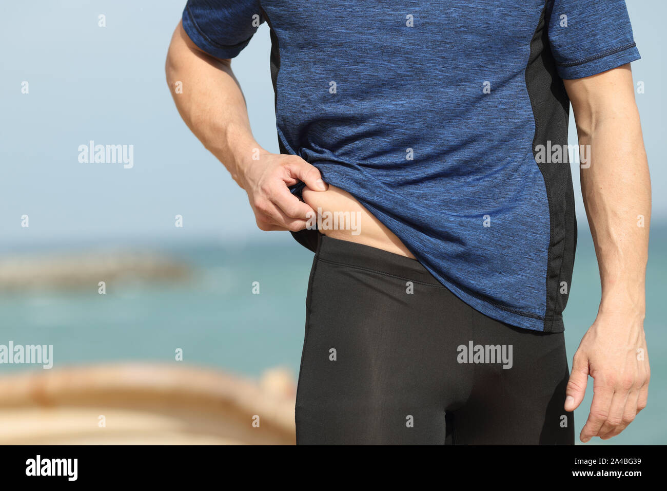 In prossimità di uno sportivo a mano pizzicare il grasso corporeo all'aperto sulla spiaggia Foto Stock