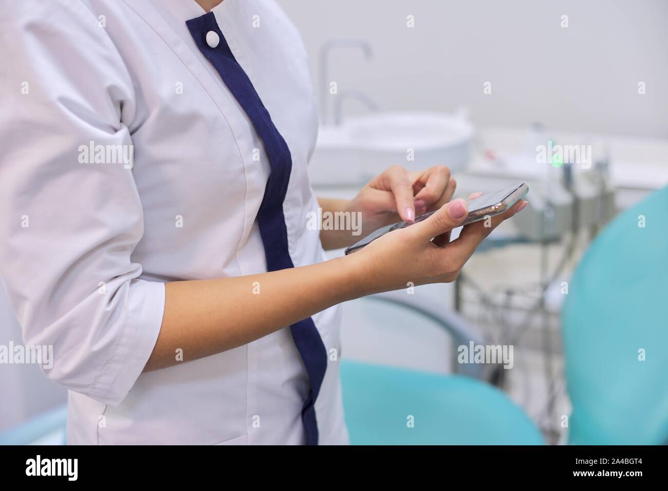 Chiudere da medici di sesso femminile mano con cellulare smartphone, Clinica Dentale sfondo office Foto Stock