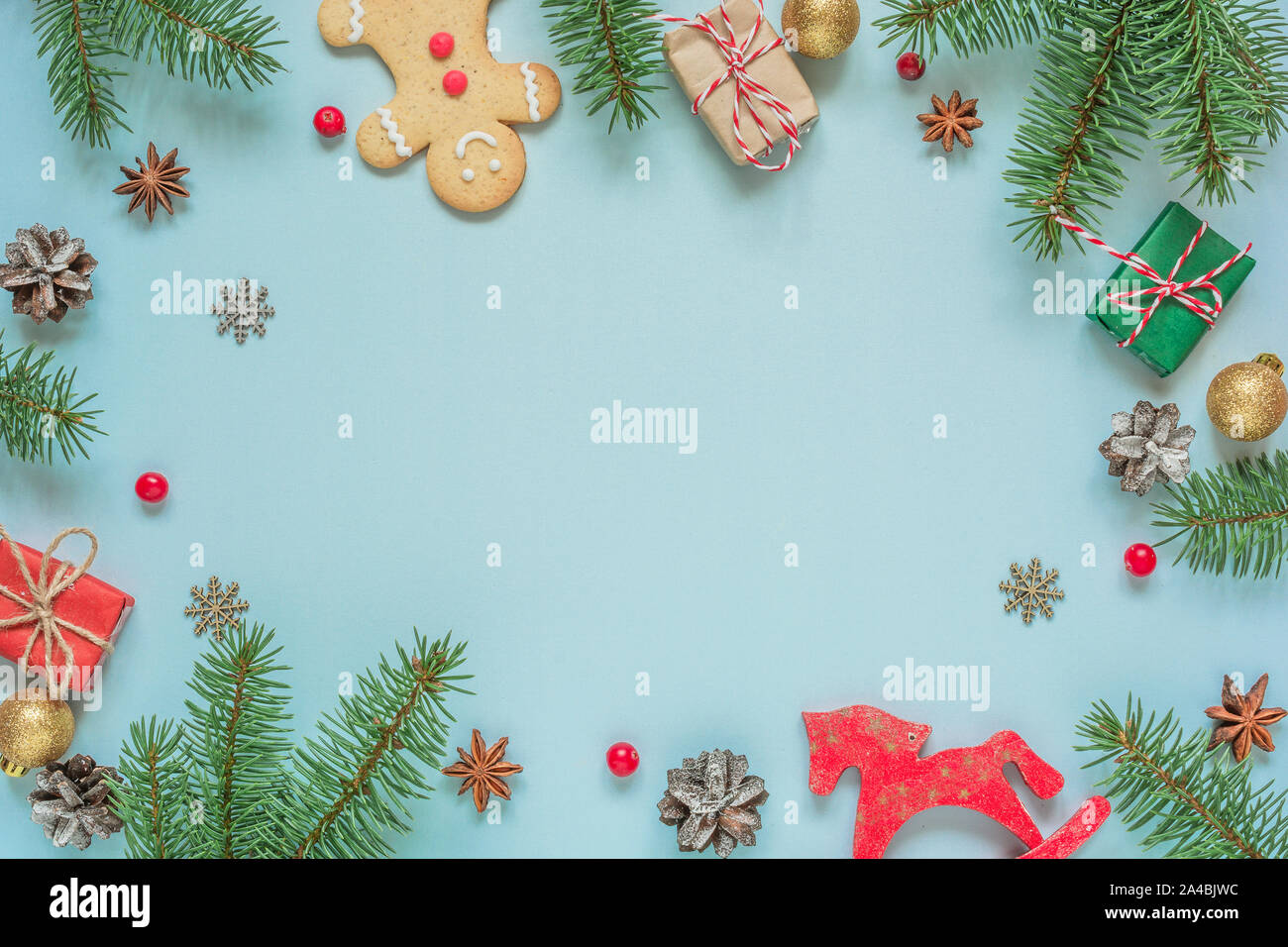 Composizione di natale. telaio realizzato in abete rami, decorazioni, bacche, pan di zenzero e pigne su sfondo blu. Sfondo di natale. Fla Foto Stock