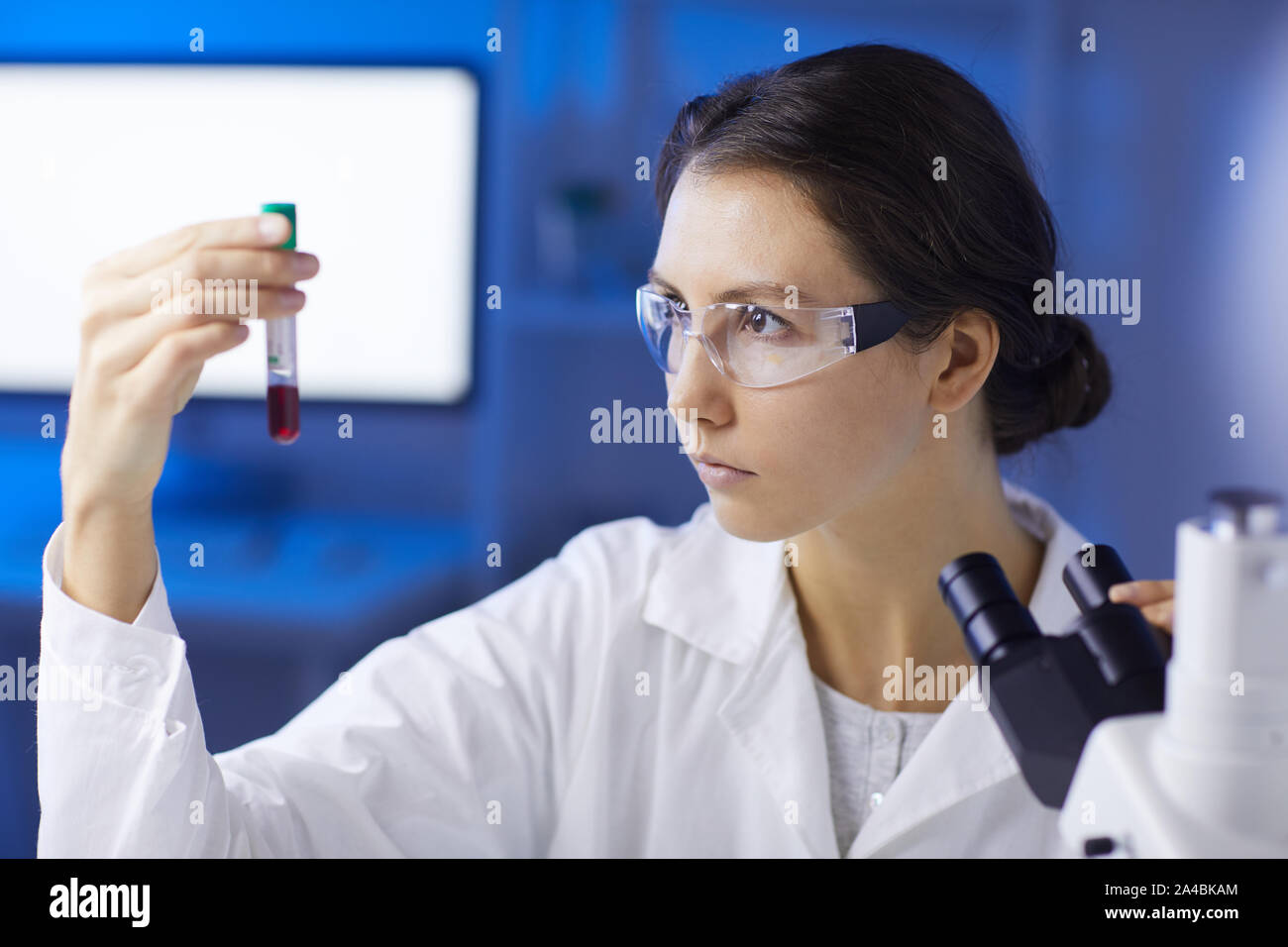 Ritratto di giovane donna azienda campione di sangue mentre facendo la ricerca medica in laboratorio, spazio di copia Foto Stock