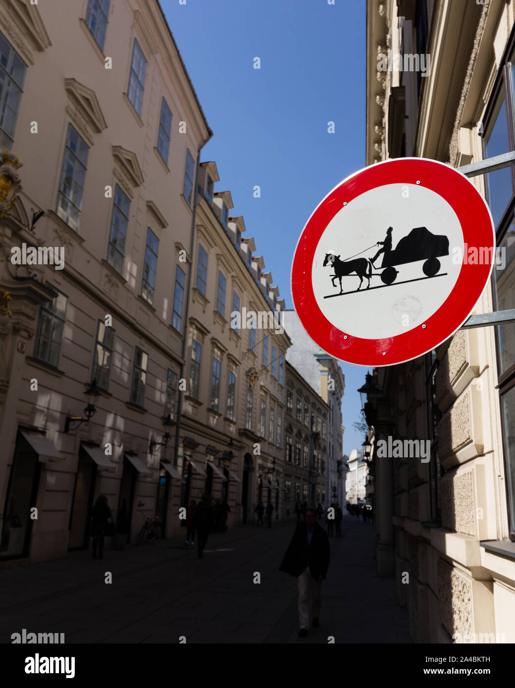 Un cartello stradale vieta cavallo carretti tirati giù per una strada urbana in ombra Foto Stock