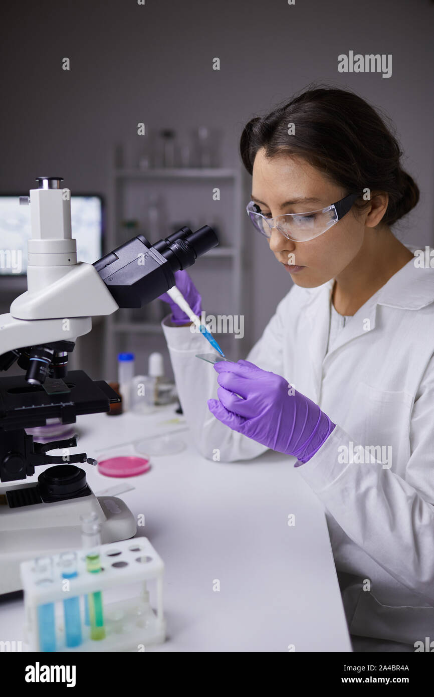 Ritratto di giovane e bella donna la preparazione dei campioni di prova durante l'utilizzo di microscopio in laboratorio Foto Stock