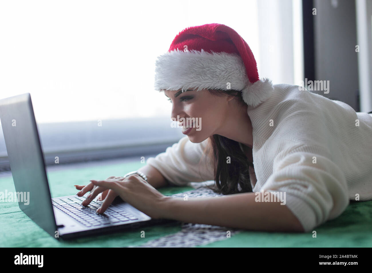Felice giovane donna domestici shopping online per Natale da portatile a casa Foto Stock