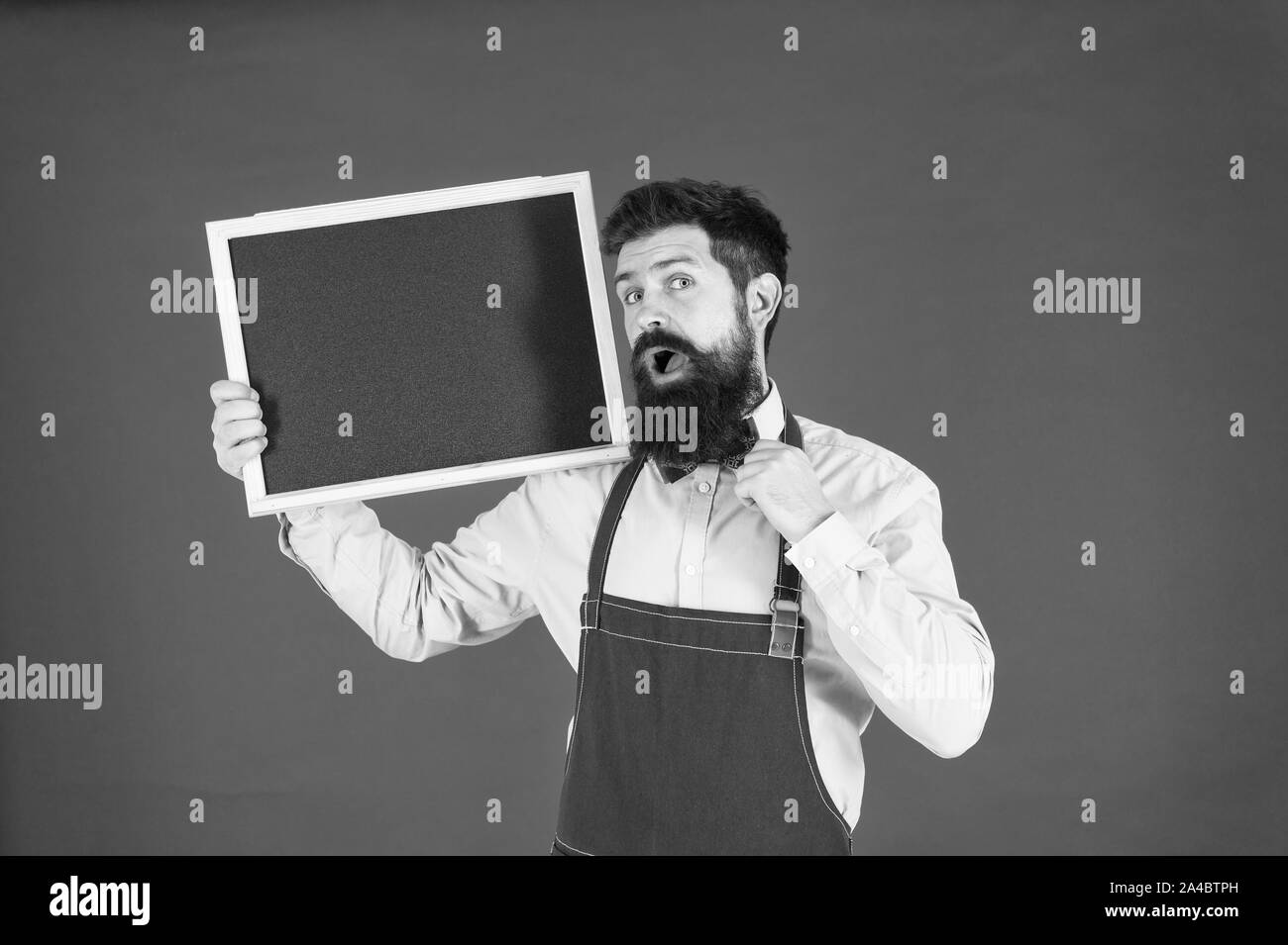 Esclusivo cocktail. Uomo Barbuto barman o cuoco in attesa della catenaria lavagna vuota. Prezzo di listino del concetto. Hipster barista visualizza blackboard copia spazio. Hipster il personale del ristorante. Hipster per informare l'utente. Foto Stock