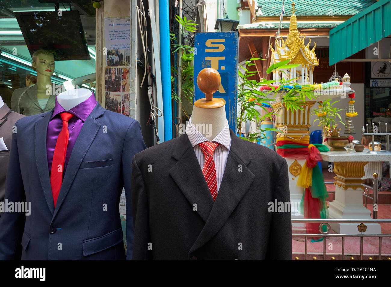 Due manichini senza testa in giacca e cravatta in un negozio di sartoria in Banglamphoo area turistica, Bangkok, Thailandia, con un stile tailandese spirito casa in b/g Foto Stock