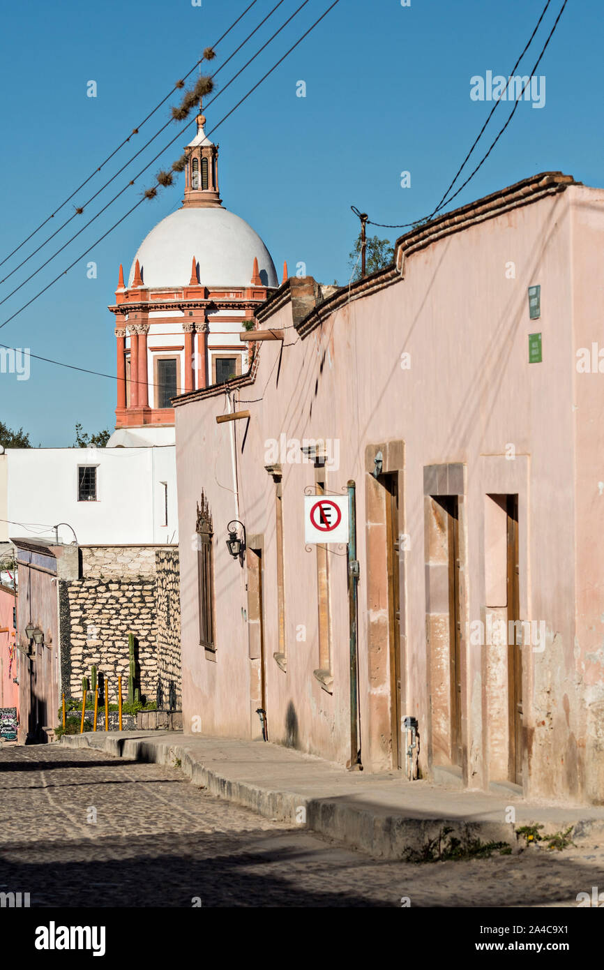 La cupola della Parroquia de San Pedro Apóstol chiesa o San Paolo Apostolo chiesa provinciale e strada di ciottoli di minerali de Pozos, Guanajuato, Messico. La città, una volta una maggiore argento centro minerario è stata abbandonata e lasciata alla rovina ma ha lentamente rimonta alla vita come un bohemian arts community. Foto Stock