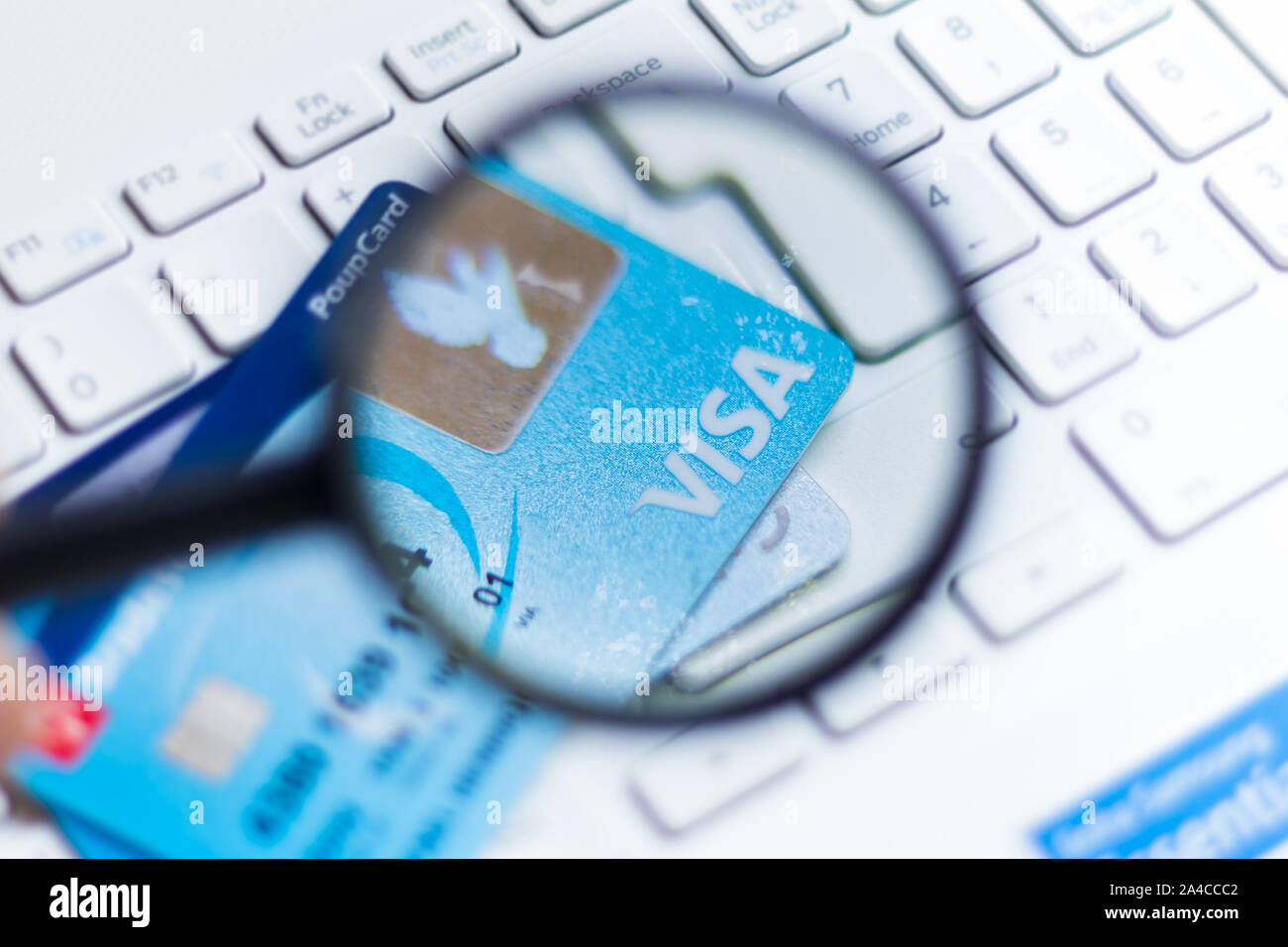 In questa foto illustrazione il logo Visa è visto visualizzata attraverso una lente di ingrandimento sulla carta di credito. Foto Stock