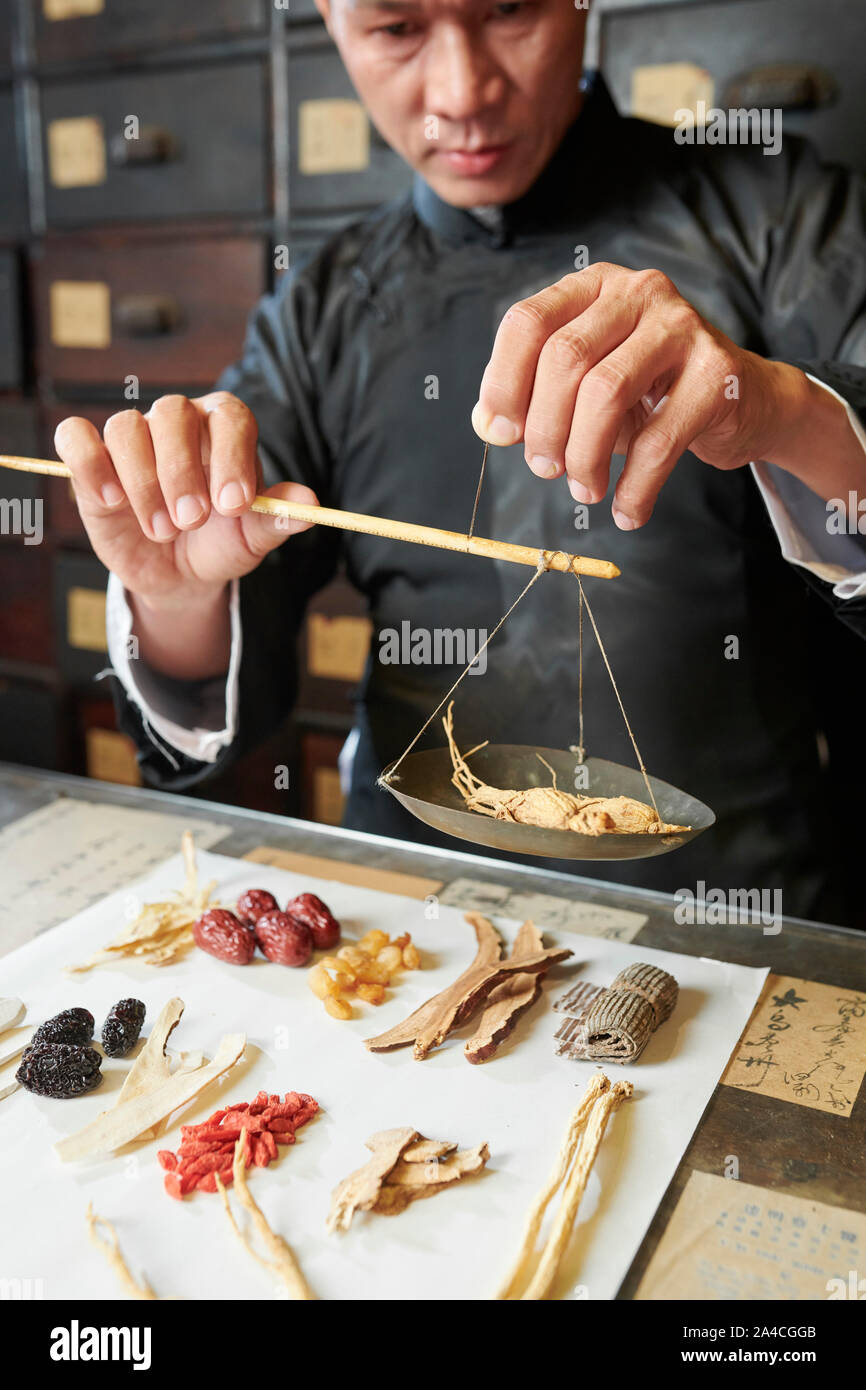 Grave tradizionali asiatici Medico medicina a secco di ponderazione radici di ginseng sulla scala Foto Stock