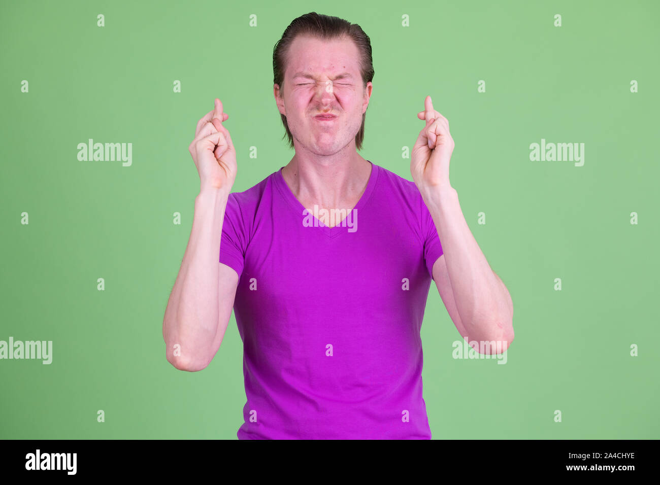 Ritratto di giovane uomo bello che desideri con le dita incrociate Foto Stock