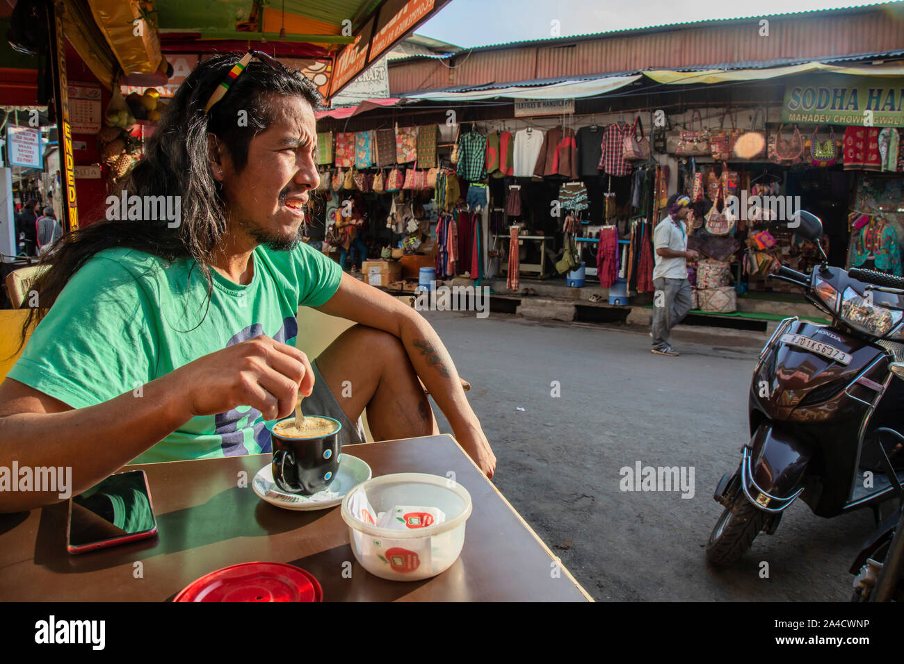 Pushkar, Rajasthan in India, 25 Gennaio 2019: latino turista americano di bere il caffè nel centro della città di Pushkar, guardando sulla strada Foto Stock