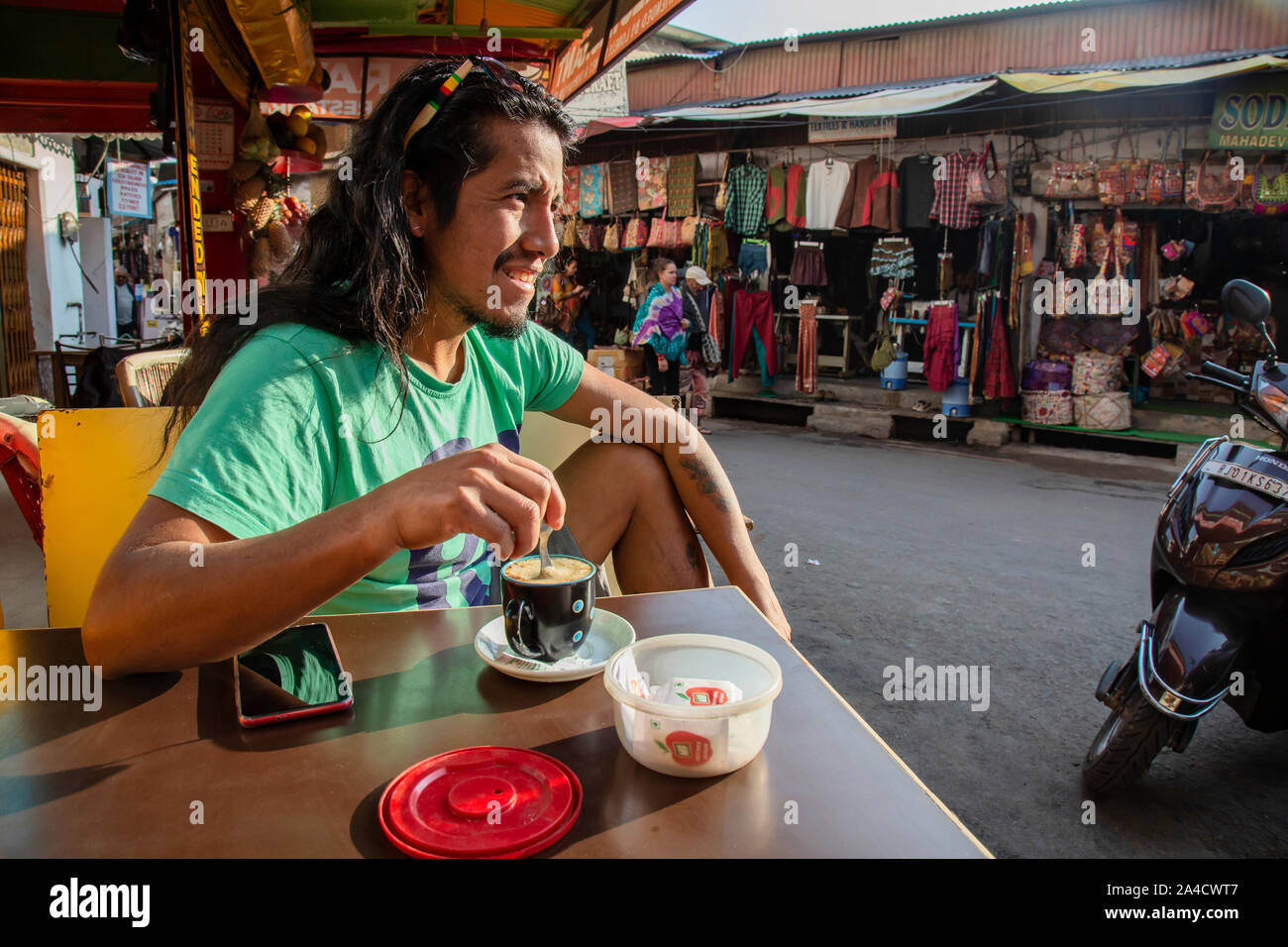 Pushkar, Rajasthan in India, 25 Gennaio 2019: latino turista americano di bere il caffè nel centro della città di Pushkar, guardando sulla strada Foto Stock