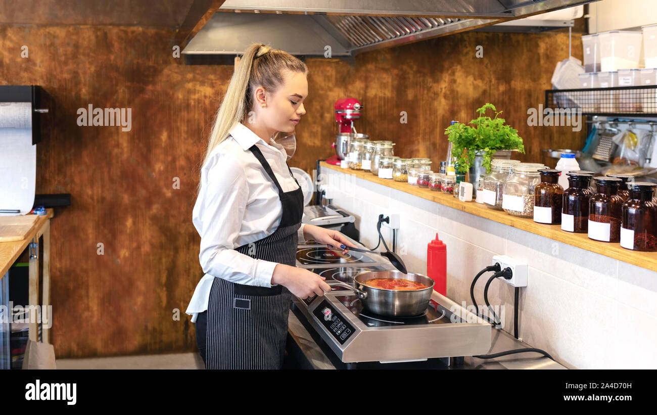 Lo chef femmina nel ristorante cucina cucina deliziosa cucina moderna stufa elettrica Foto Stock
