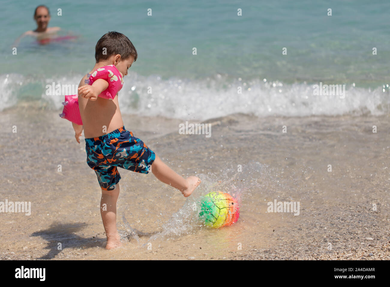 Padre e figlio giocare con una palla spiaggia nell'oceano, Grecia Foto Stock