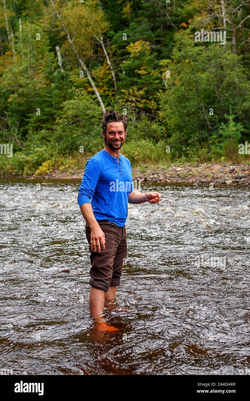 Uomo sorridente lavare i capelli in un fiume, Stati Uniti Foto Stock