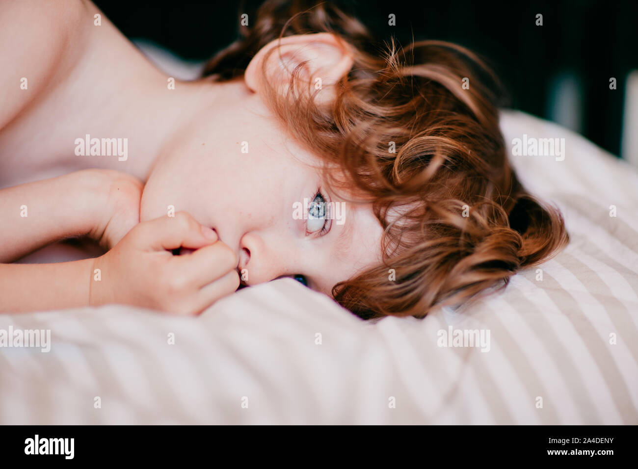 Ritratto di un ragazzo che giace nel letto con la sua mano davanti al suo volto Foto Stock