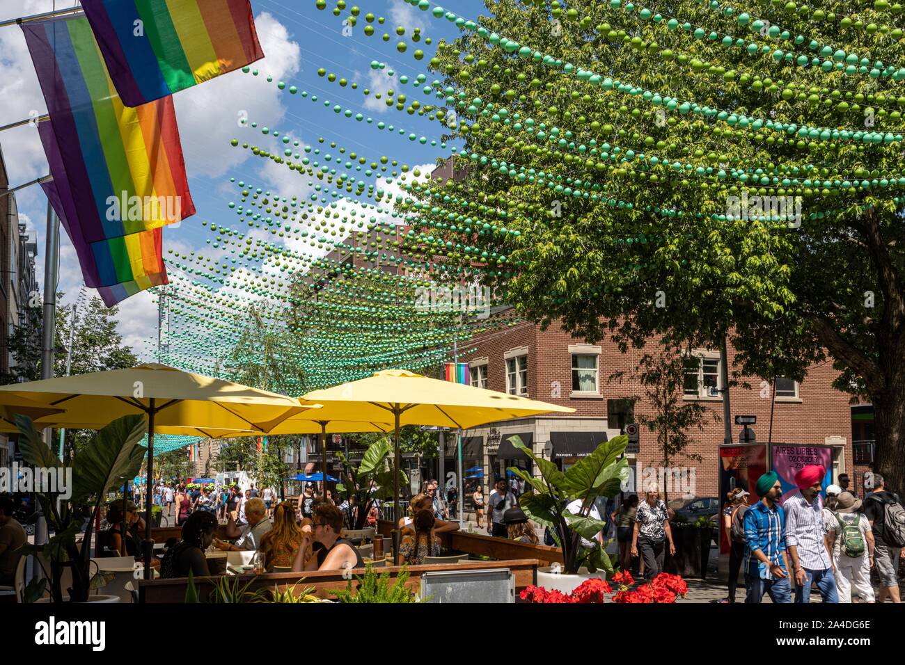 Terrazza di un caffè e il quartiere del villaggio gay riservato ai pedoni in estate e decorati con i colori dell'arcobaleno, RUE SAINTE-CATHERINE, Montreal, Quebec, Canada Foto Stock