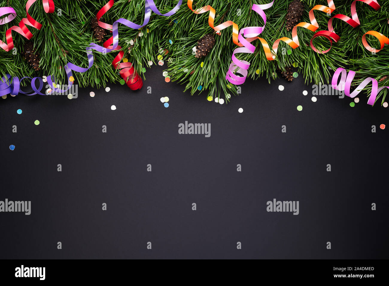 Bordo di Natale con pino rami decorati e la festa di coriandoli su uno sfondo nero. Copia spazio per il testo Foto Stock