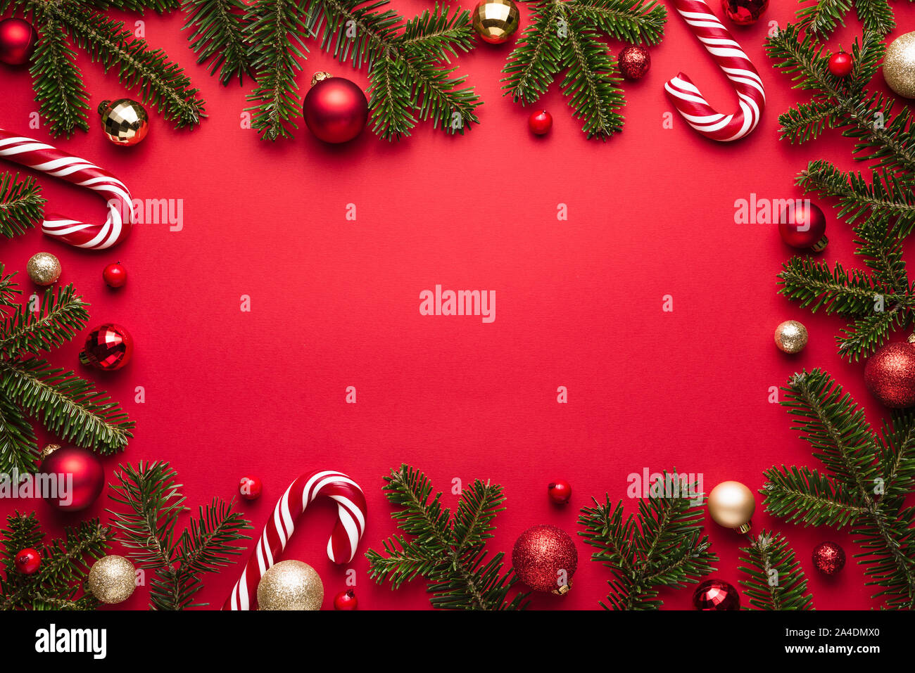 Natale e Anno Nuovo telaio su sfondo rosso. Decorazioni di festa dei rami di abete, palle di Natale e candy cane Foto Stock