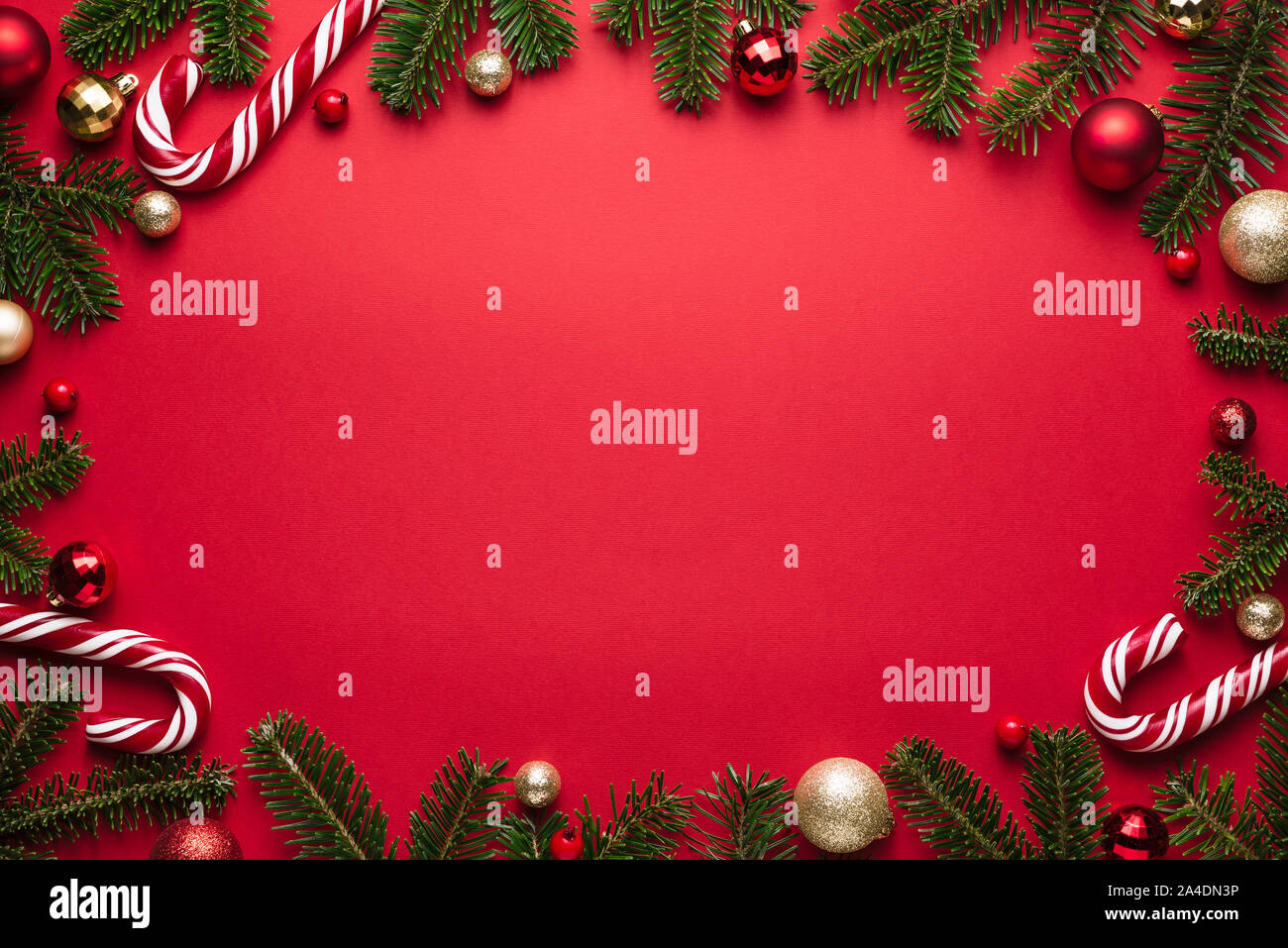 Natale e Anno Nuovo telaio ovale su sfondo rosso. Decorazioni di festa dei rami di abete, palle di Natale e candy cane Foto Stock