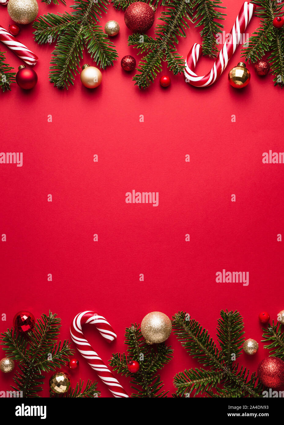 Natale e Anno Nuovo telaio di frontiera su sfondo rosso. Decorazioni di festa dei rami di abete, palle di Natale e candy cane Foto Stock