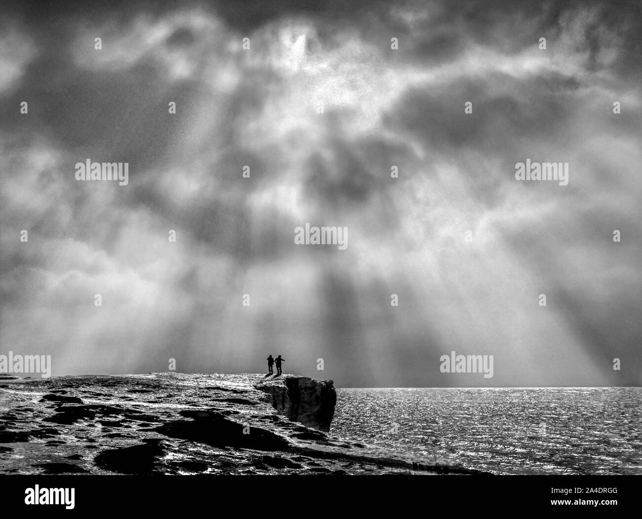Due persone che guardano i raggi nel tardo pomeriggio sulla East Sussex costa in Inghilterra. Foto Stock