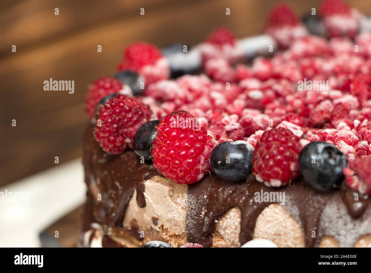 Una vista ravvicinata di Torta vegana al cioccolato ricoperte con lamponi e mirtilli, congelati in frigorifero, su una tavola con fondo sfocato. Copia Foto Stock