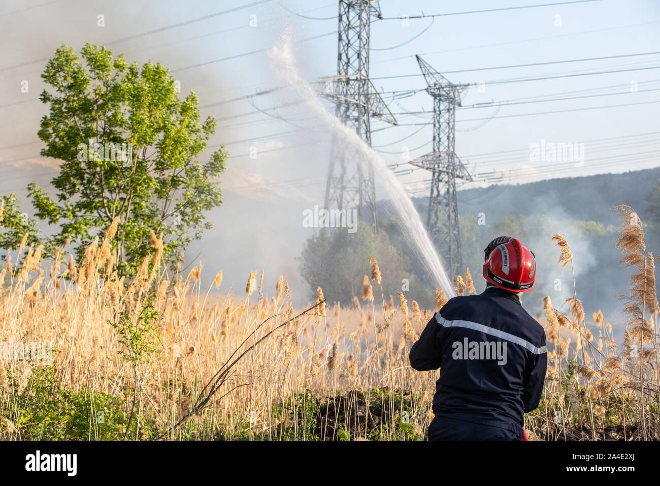 FIREFIGHTER estinzione di un incendio a spazzola (ANCE) sotto alta tensione tralicci, i servizi di emergenza CENTRO DI CHAMBERY, LES MARCHE, SAVOY (73), Francia Foto Stock