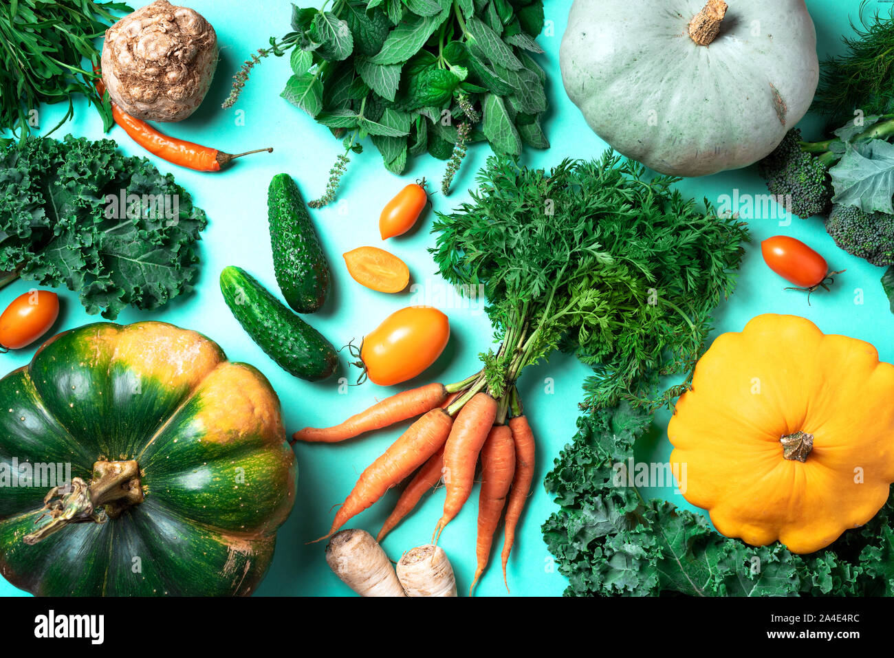 Autunno verdure alla moda su sfondo verde. Vista dall'alto. Vegane e dieta vegetariana, concetto di raccolto. Ingredienti per la cottura - zucca, pomodori, cucum Foto Stock