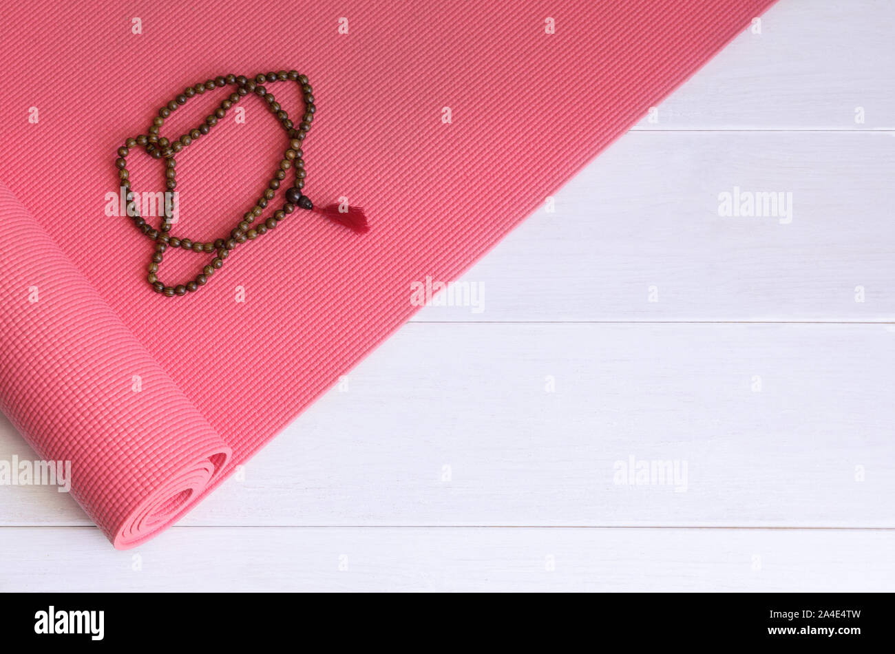 Yoga tappetino rosa con legno mala collana di perle. Yogi sfondo accessori. Copia dello spazio. Foto Stock