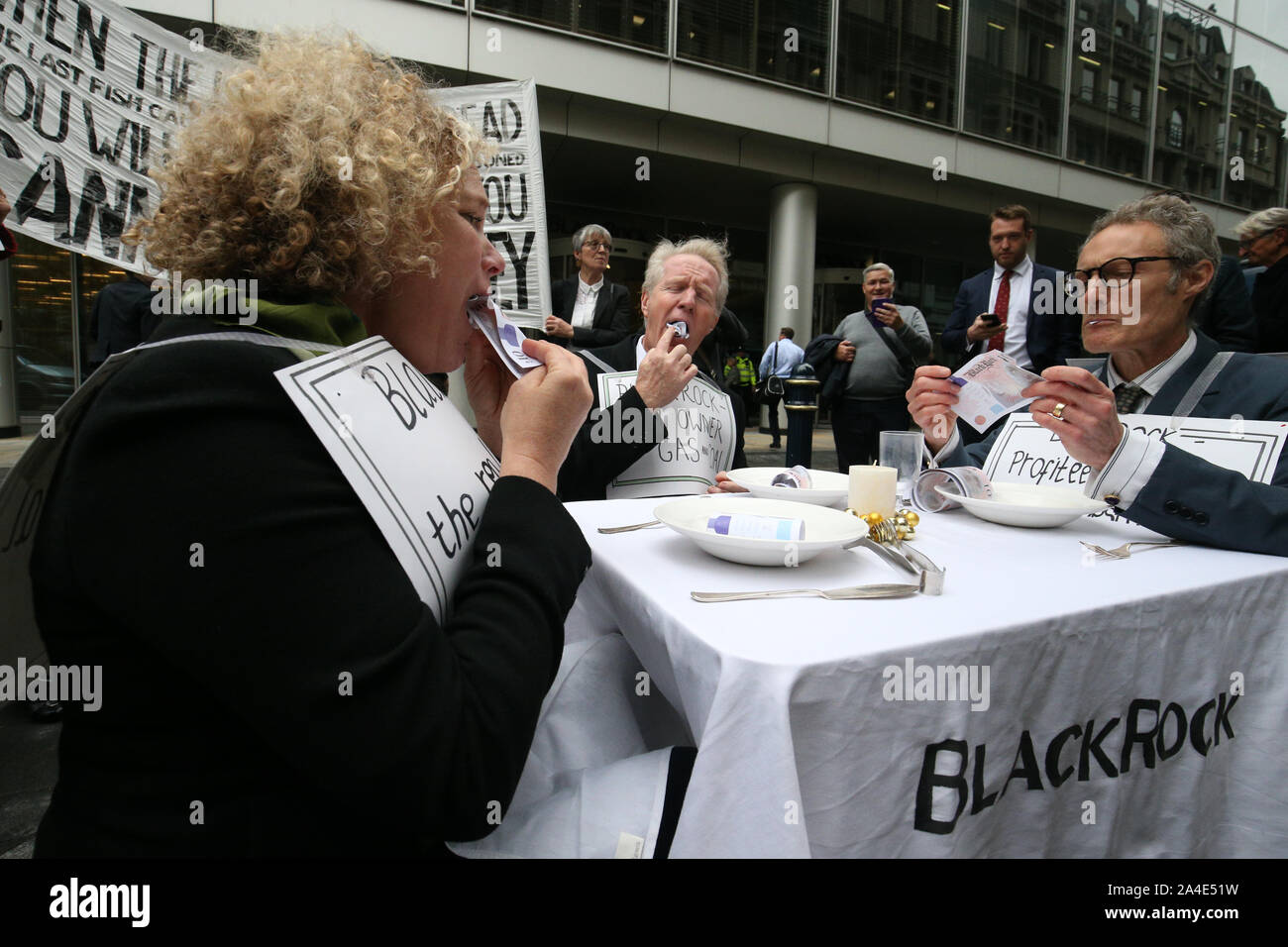 Manifestanti "mangiare il denaro come una forma di manifestazione al di fuori della sede di BlackRock in Throgmorton Avenue a Londra, durante una ribellione di estinzione (XR) cambiamenti climatici protesta. Foto Stock