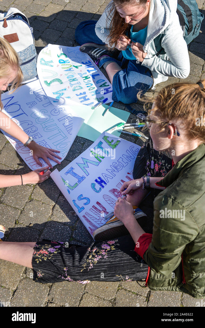 Giovani che si preparano a mano segni scritti come essi partecipano alla estinzione della ribellione clima sciopero in Truro City in Cornovaglia. Foto Stock